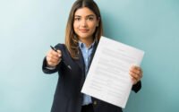 Jovem segurando contrato e caneta, representando situação de contrato de estágio não assinado pela faculdade.