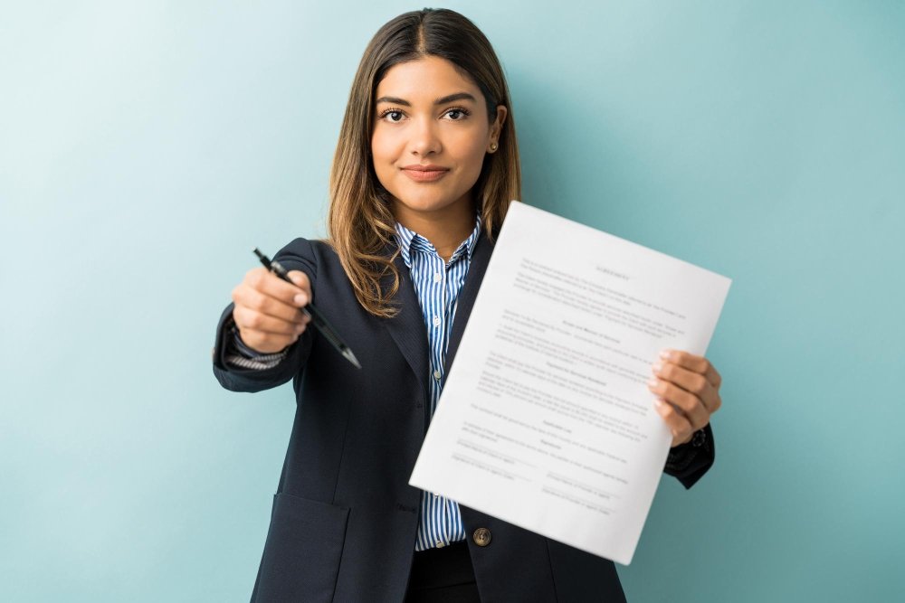 Jovem segurando contrato e caneta, representando situação de contrato de estágio não assinado pela faculdade.