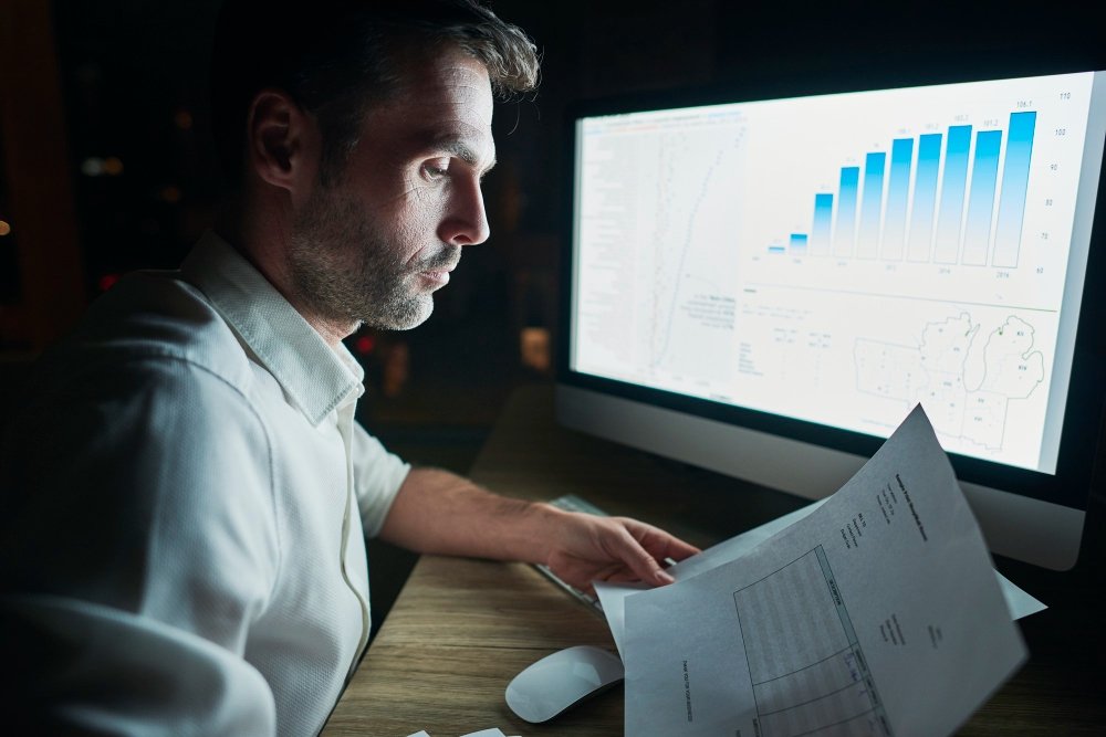 Jovem profissional em frente ao computador analisando gráficos e relatórios durante estágio análise de dados.