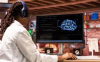 Estudante programa modelo de inteligência artificial no computador durante estágio em machine learning.