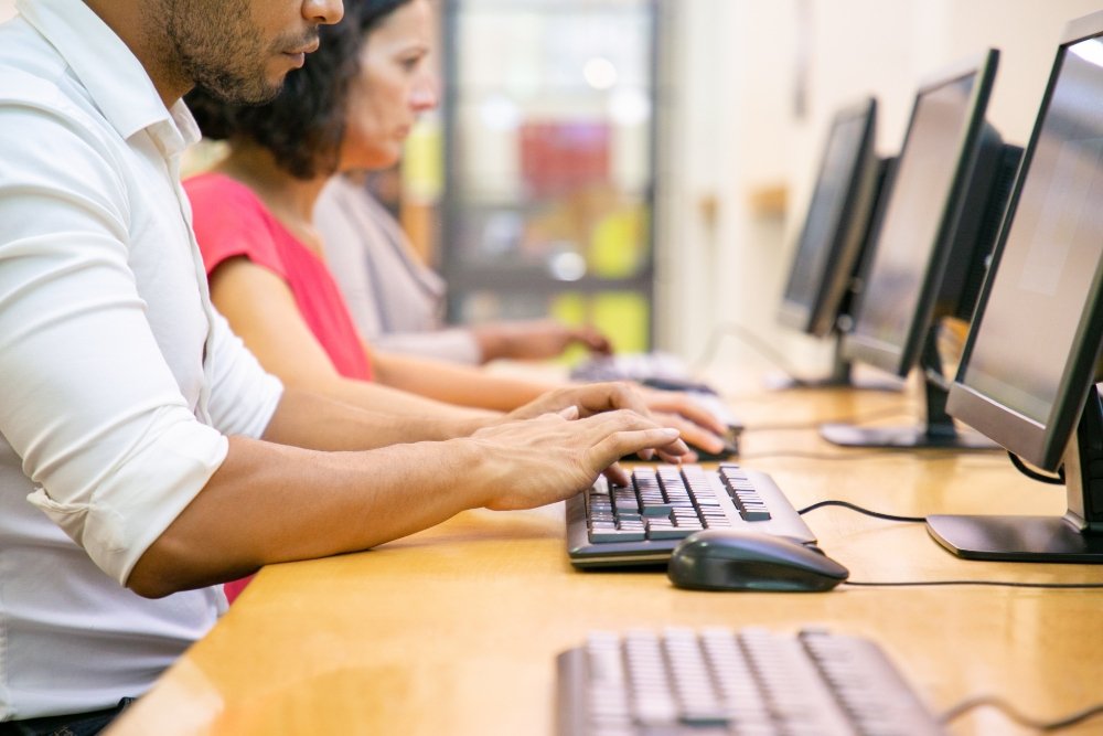 Alunos digitando em computadores durante atividades práticas de estágio informática em laboratório de tecnologia