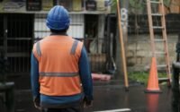 Especialista em SST com colete e capacete em área de trabalho.